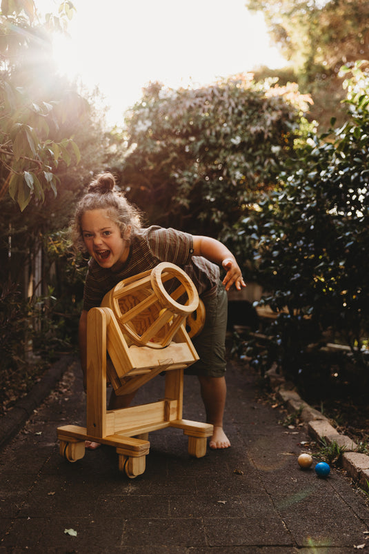 Child playing with a wooden toy in a garden