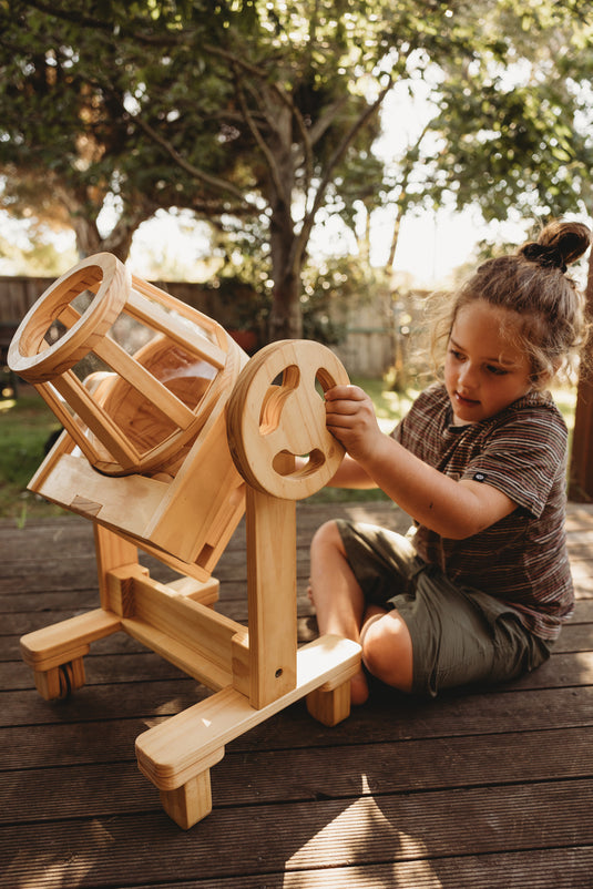 Child playing with a wooden toy on a wooden deck