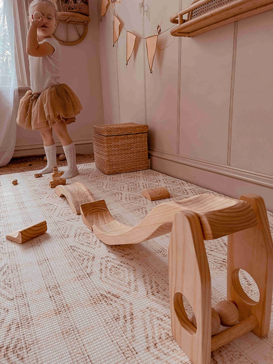 Child playing with a wooden ball run on mat