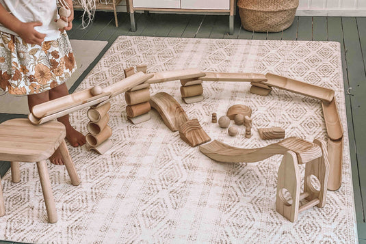 Wooden play set on a patterned rug with a child partially visible