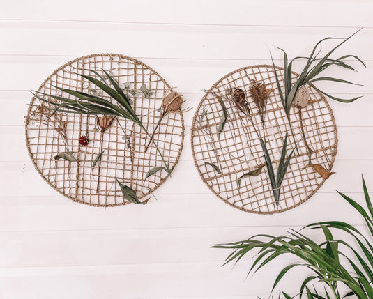 Two round weaving frames with decorative items on a light wooden surface.