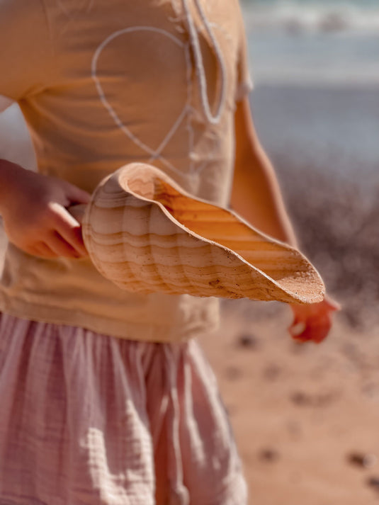 Person holding a large shovel  with a blurred beach background
