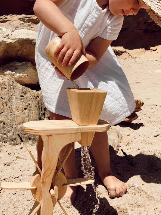 Child playing with a wooden water wheel