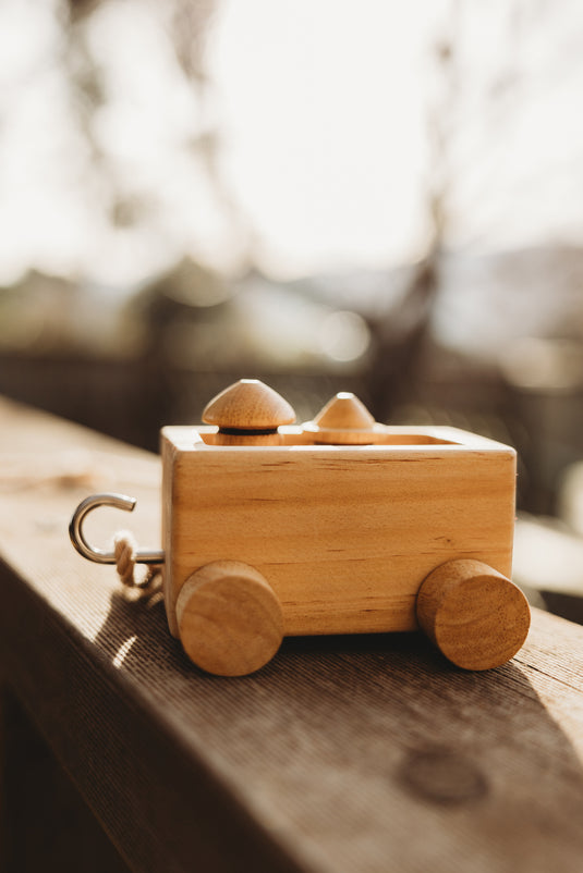 Wooden toy train car on a wooden surface with a blurred natural background