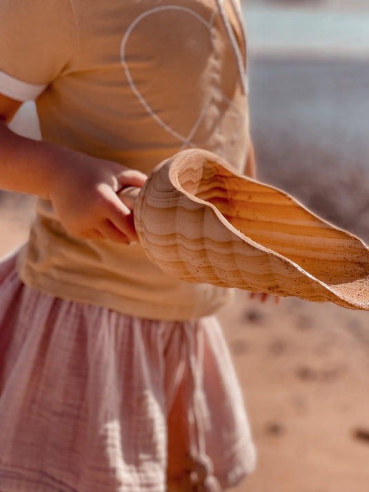 Person holding a large shovel on a beach