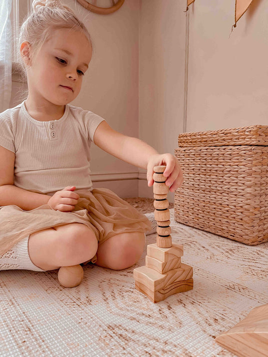 Child playing with wooden building blocks on a soft surface
