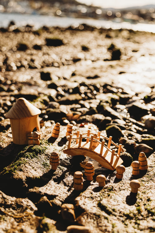 Wooden toy boat and house on a rocky beach with water in the background