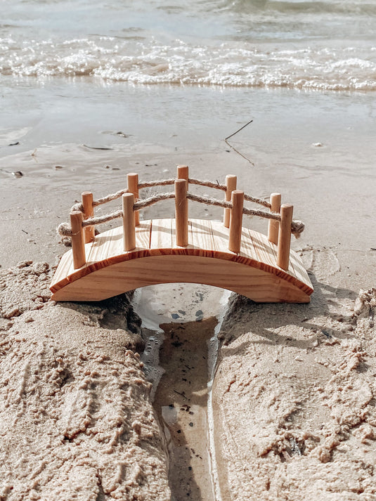 Small wooden bridge on a sandy beach with water in the background