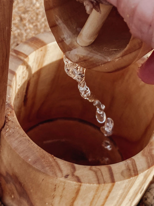Wooden bucket being lifted with water dripping, close-up shot.