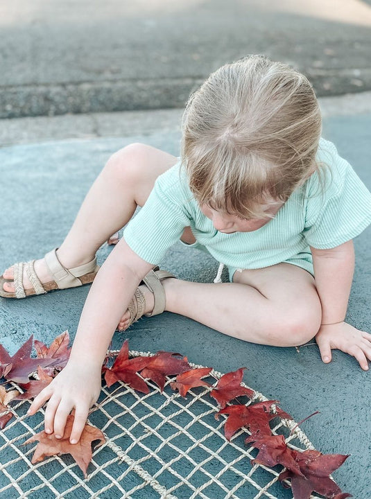 Child playing with red leaves on a textured surface
