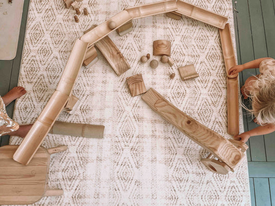 Children playing with wooden building blocks on a patterned rug